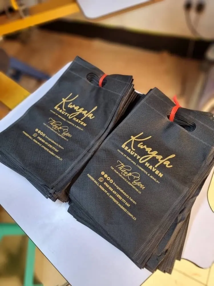 Sacs en tissu noirs imprimés avec un marquage doré - Kora Branding, Kigali